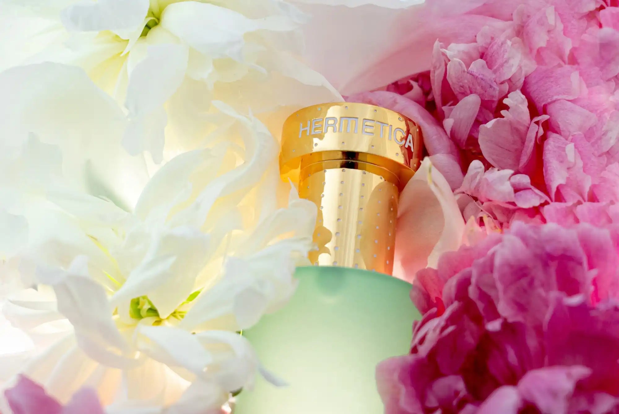 Frosted glass perfume bottle with a gold cap nestled among flowers.